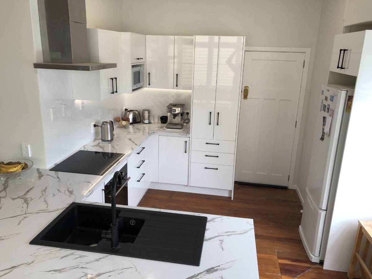 Renovated kitchen with white cupboards and marble benchtop