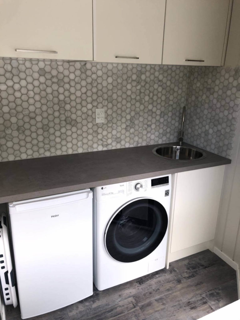 Renovated laundry with pretty hexagonal tiling splashback